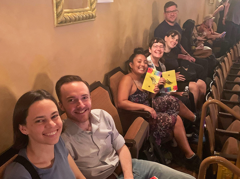 Colleagues in a theater holding the Operation Mincemeat playbill