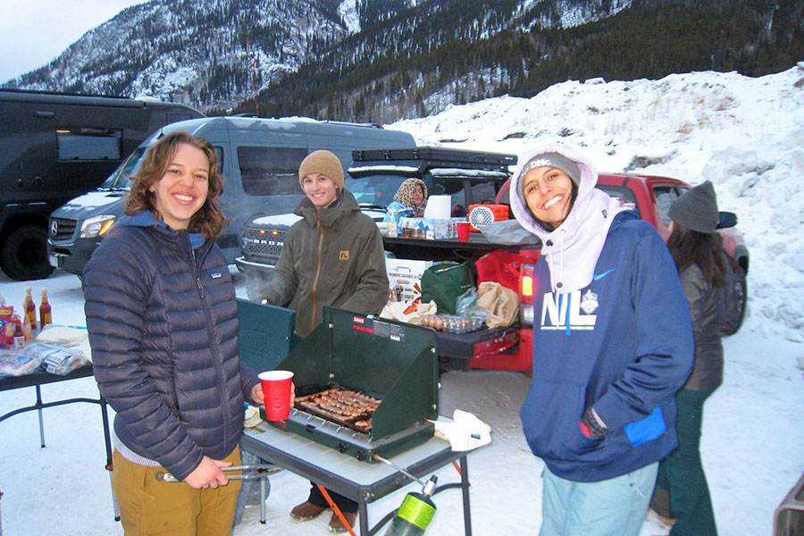 People pose near a grill in the snow