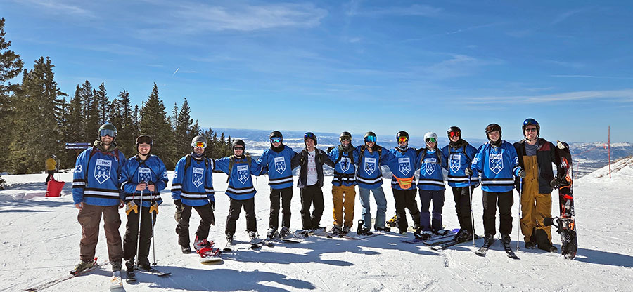 A group poses on a ski slope wearing blue jerseys