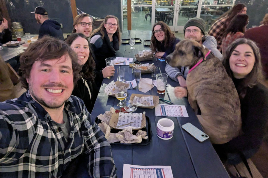 People and a dog sit around a wooden table