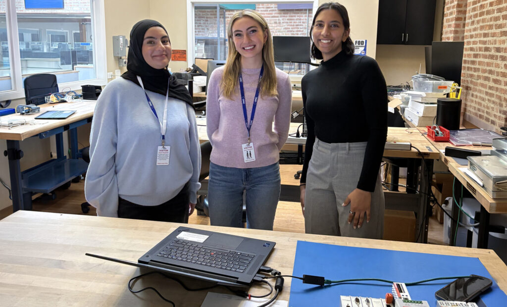 Three engineering students standing in a test lab at DMC.