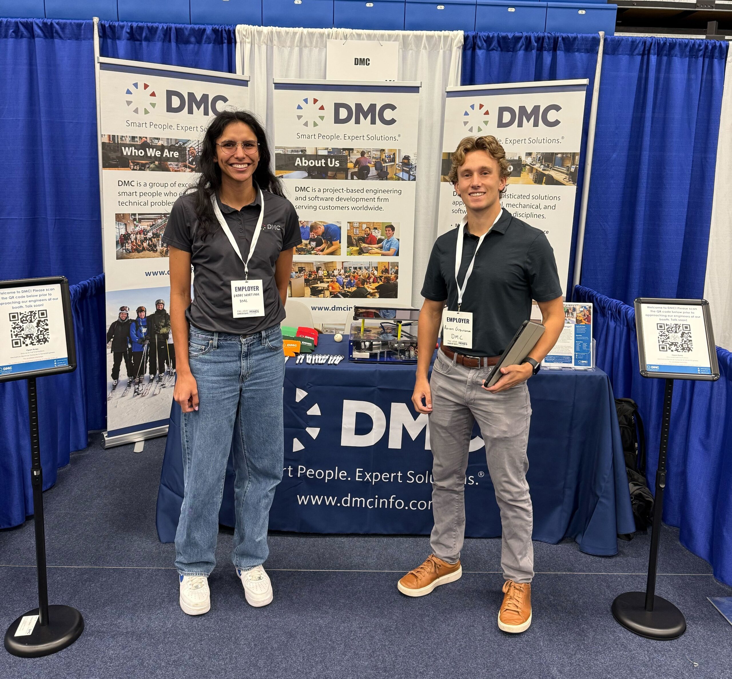 Two DMC teammates at their booth at a university career fair.