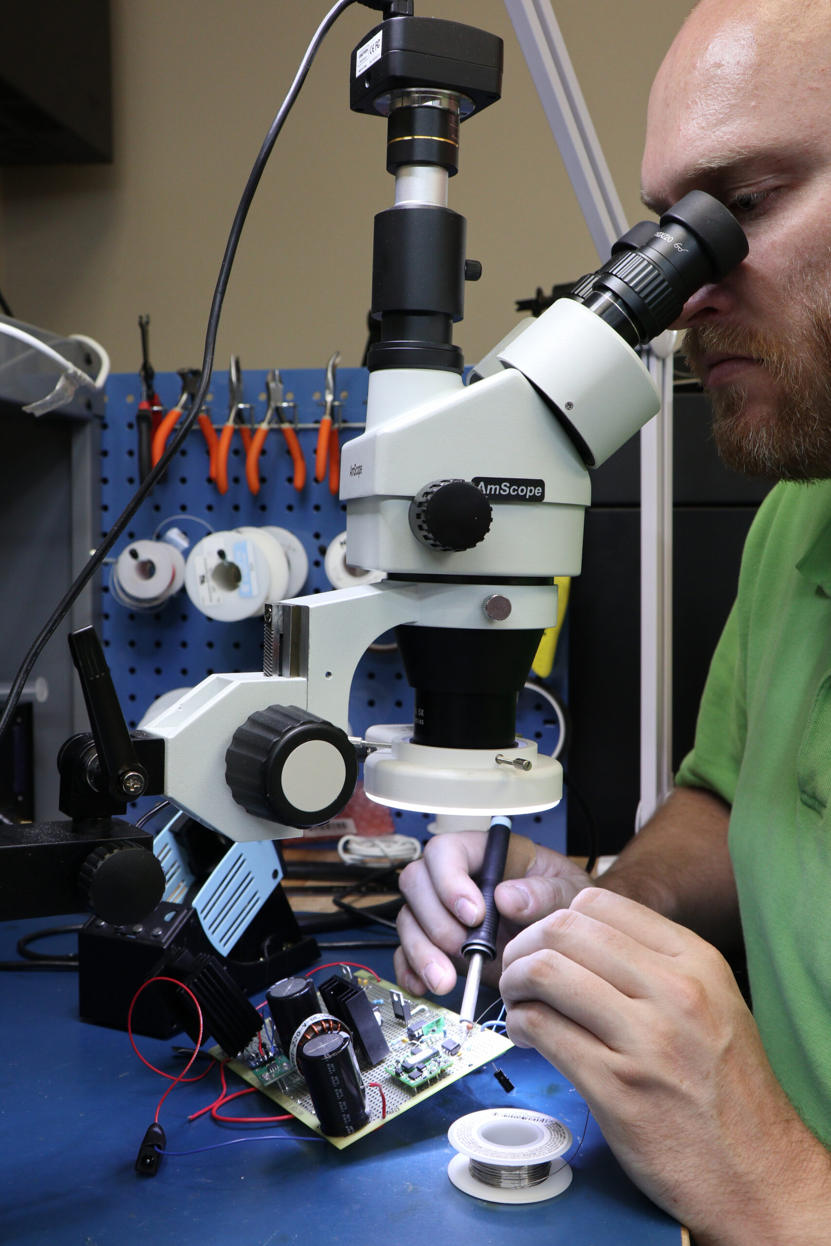 A DMC engineering examining a PCB board with a microscope.