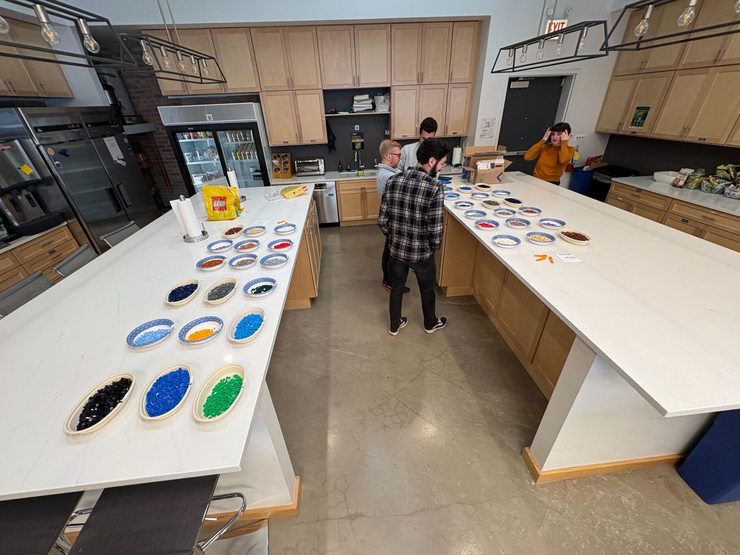 DMC employees standing around a countertop with different dishes of assorted LEGO pieces.