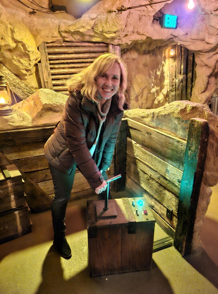 A member of DMC's Denver team holding the handles of a fake dynamite plunger in one of the caverns at Casa Bonita.
