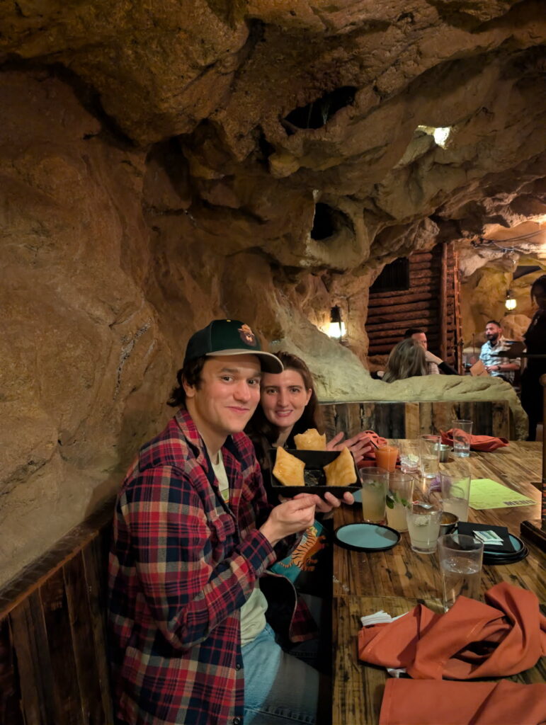 Two DMC team members holding up empanadas at their table at Casa Bonita.