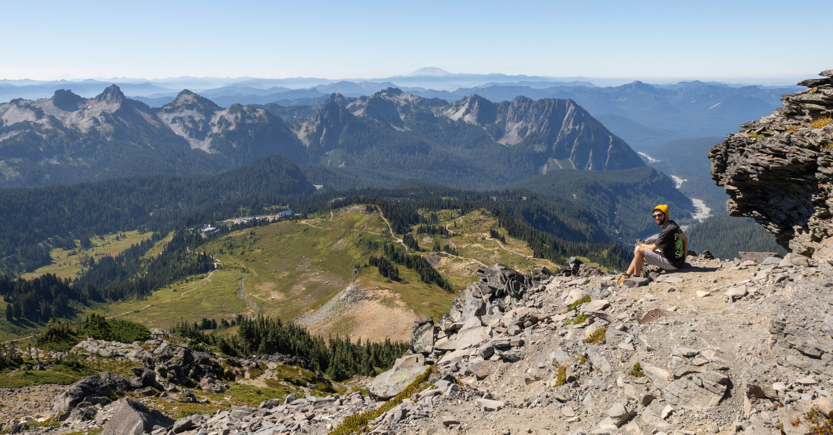 DMC engineer sitting at the summit of Mount Rainier base hike