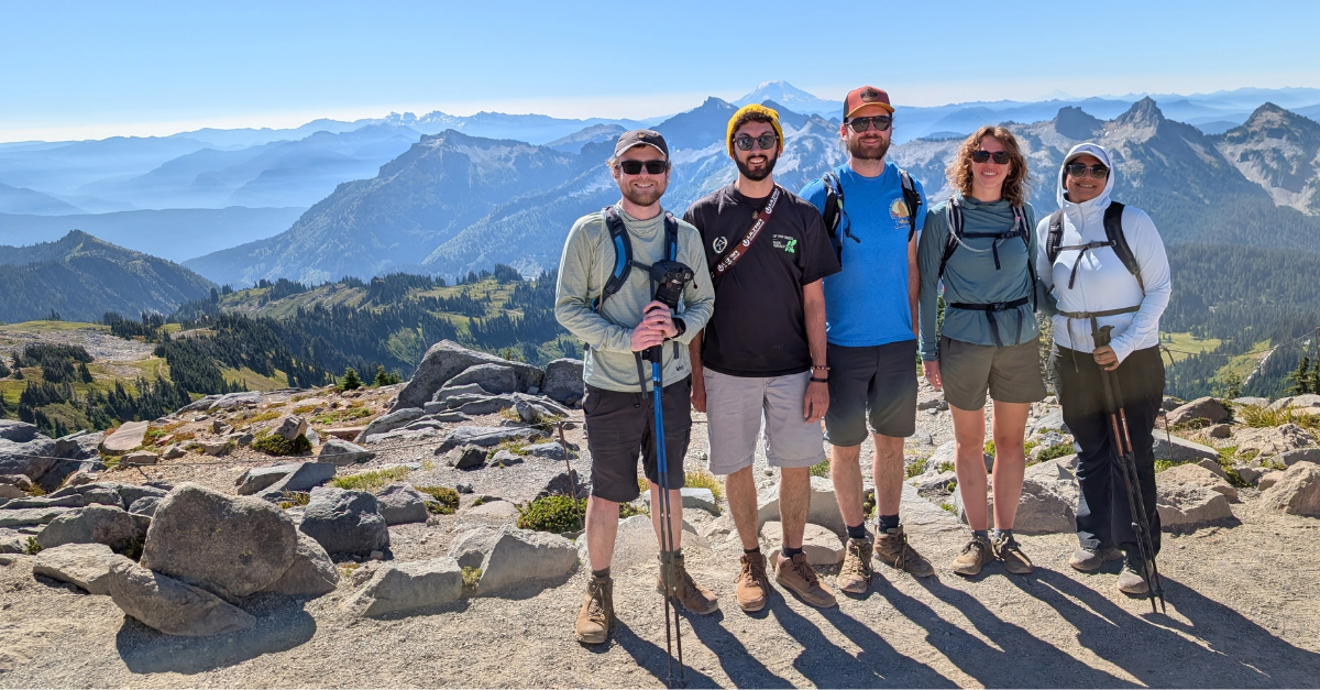 DMC team members posting at the top of a trail along the base of Mount Rainier