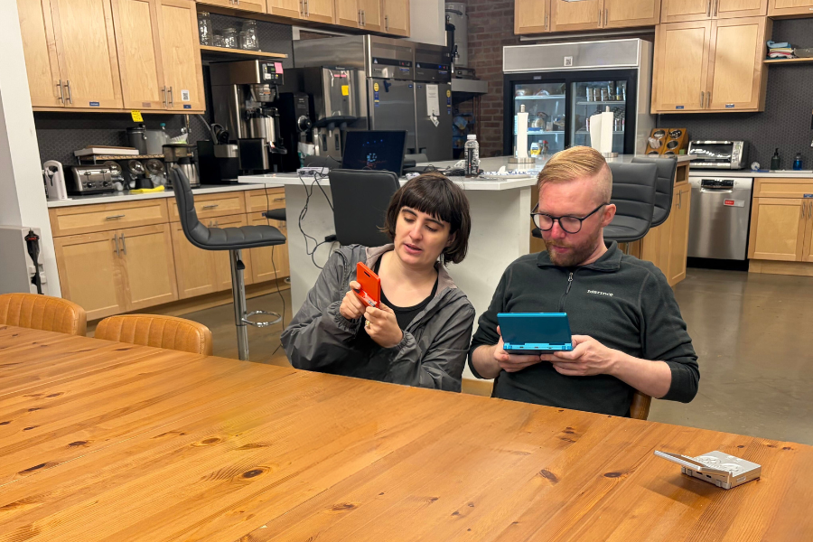 Two DMC employees playing handheld games