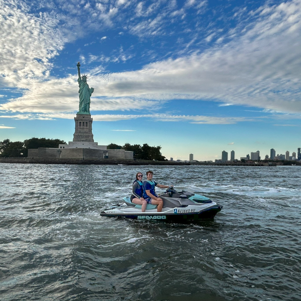 DMC team members on a jet ski in front of Statue of Liberty