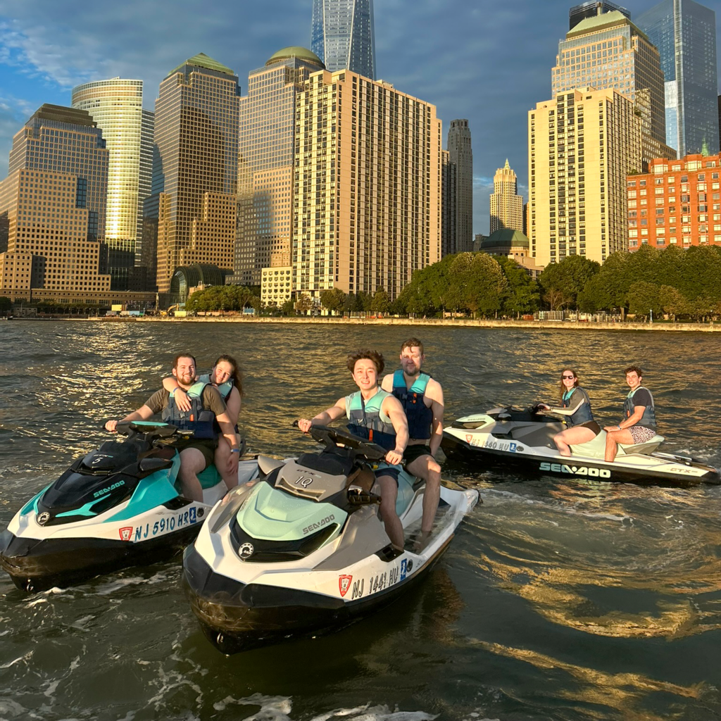 Three jet skis in New York Harbor in front of the Financial District